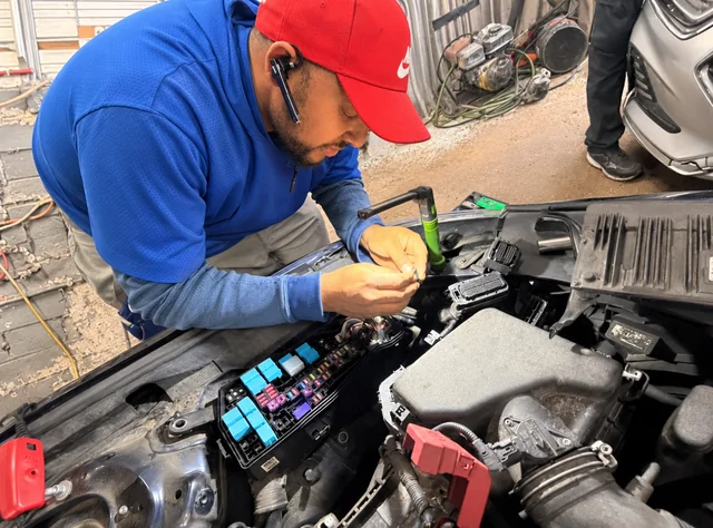 M&A technician working beside a vehicle fuse box