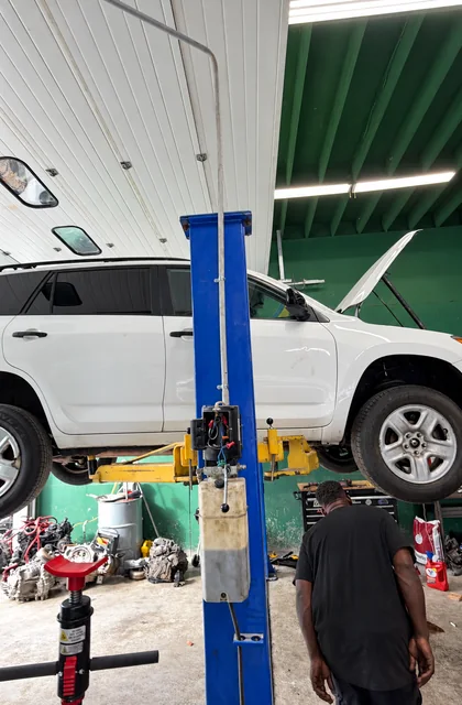 White SUV raised on a blue lift with a technician at the M&A workshop