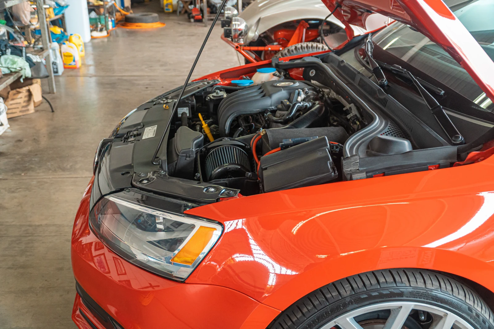 Open engine bay of a red car in a workshop.