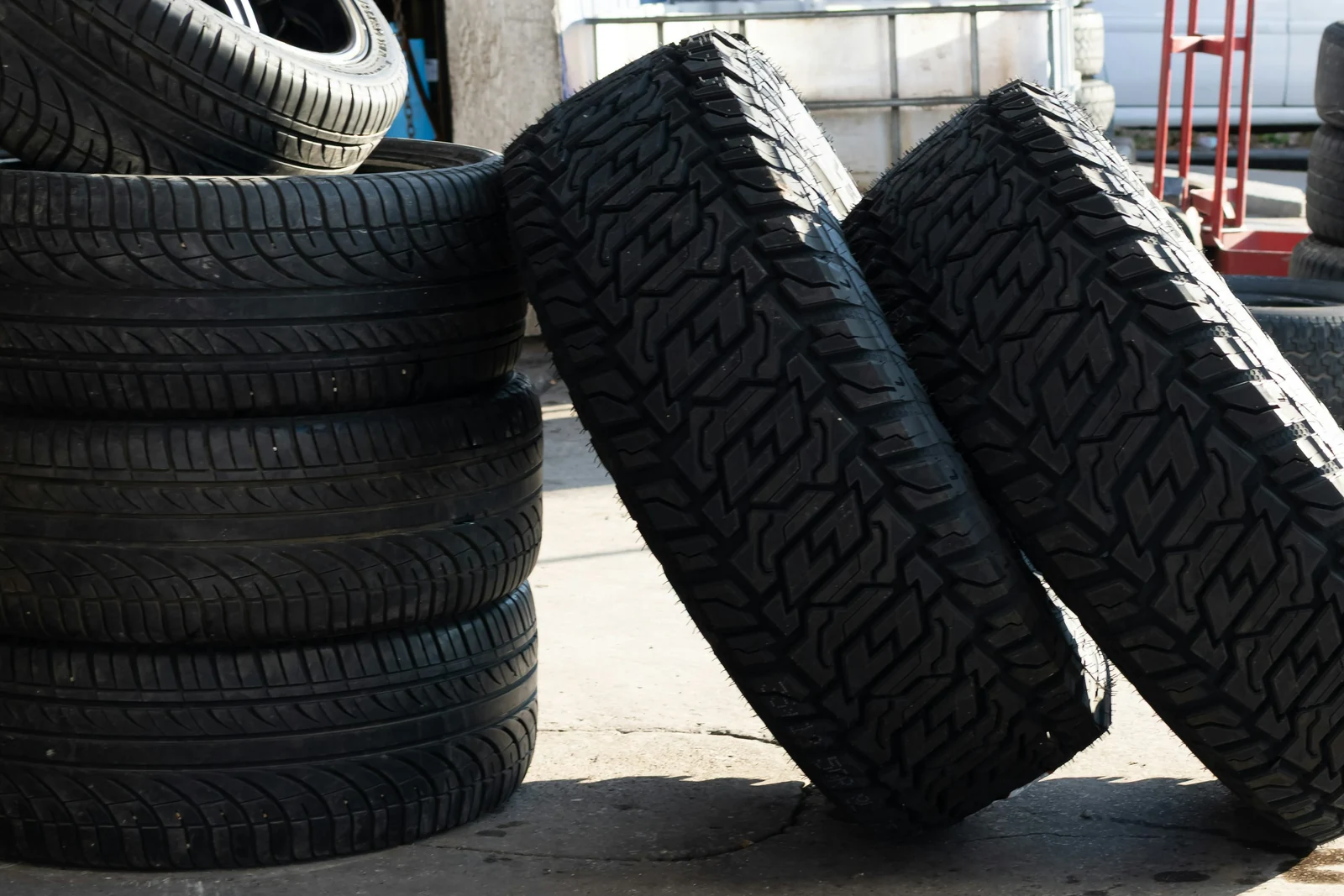 Road tires and deep-tread tires stacked outside a tire workshop.