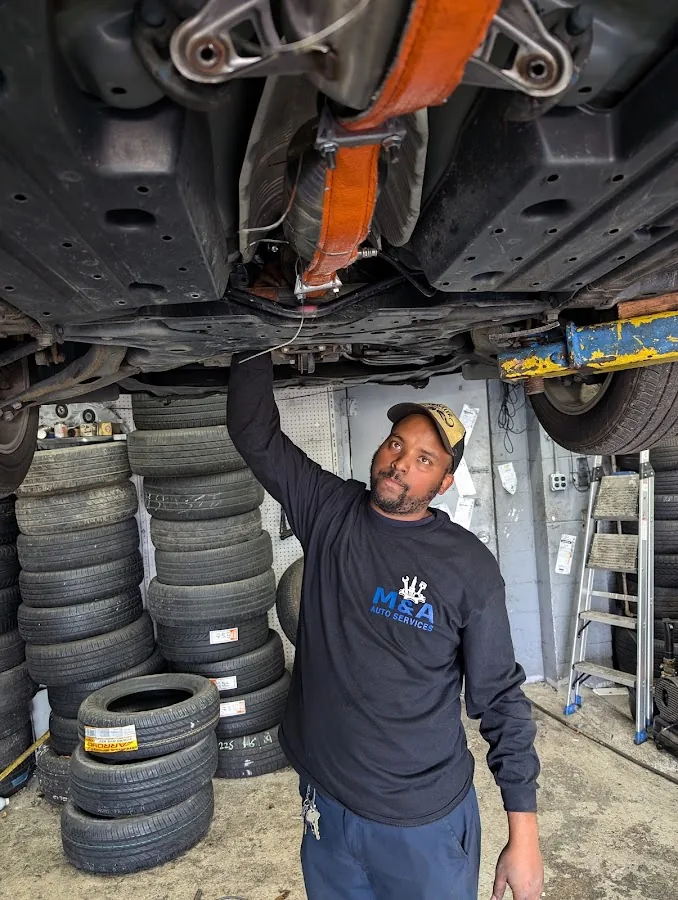 M&A technician working beneath a vehicle on the lift